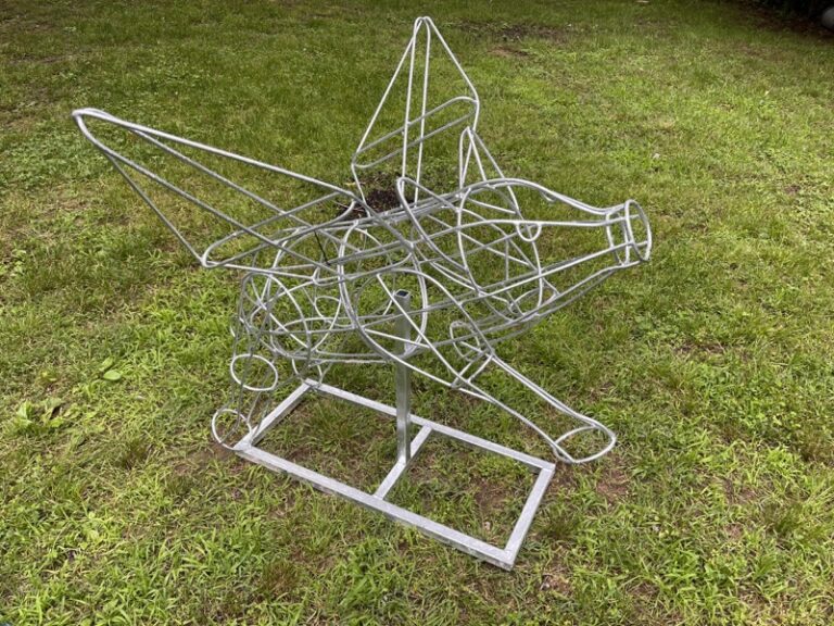 Bare wire flying-pig topiary frame on a metal stand, front three-quarter view