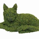 Moss-covered cat topiary lying down, with glass eyes, on a plain white background