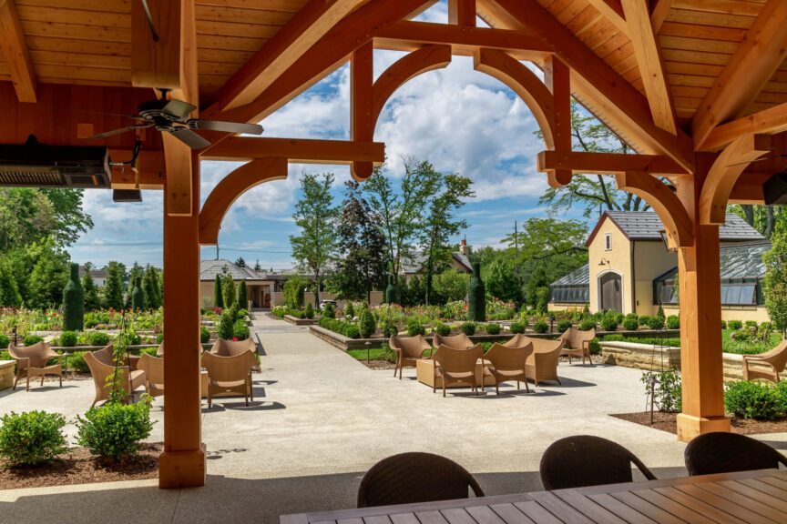 View from beneath a timber garden pavilion looking out over a landscaped estate with topiaries