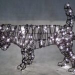 Wire-frame beagle topiary wrapped in miniature lights, photographed lit against a dark backdrop