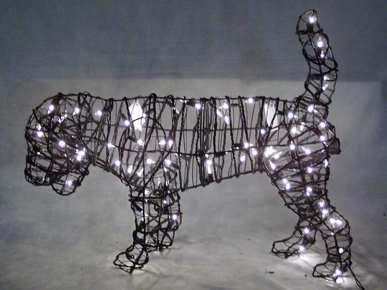 Wire-frame beagle topiary wrapped in miniature lights, photographed lit against a dark backdrop