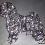 Wire-frame dog topiary strung with small white lights, illuminated against a dark background.
