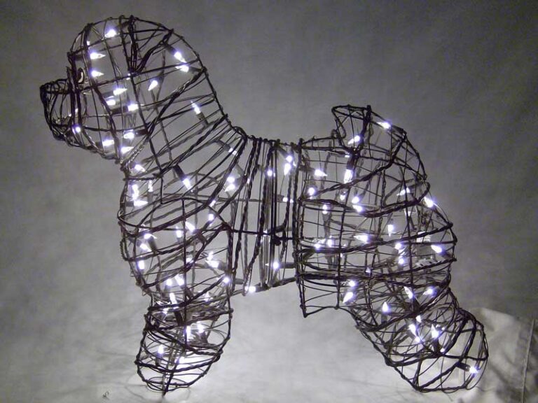 Wire-frame dog topiary strung with small white lights, illuminated against a dark background.