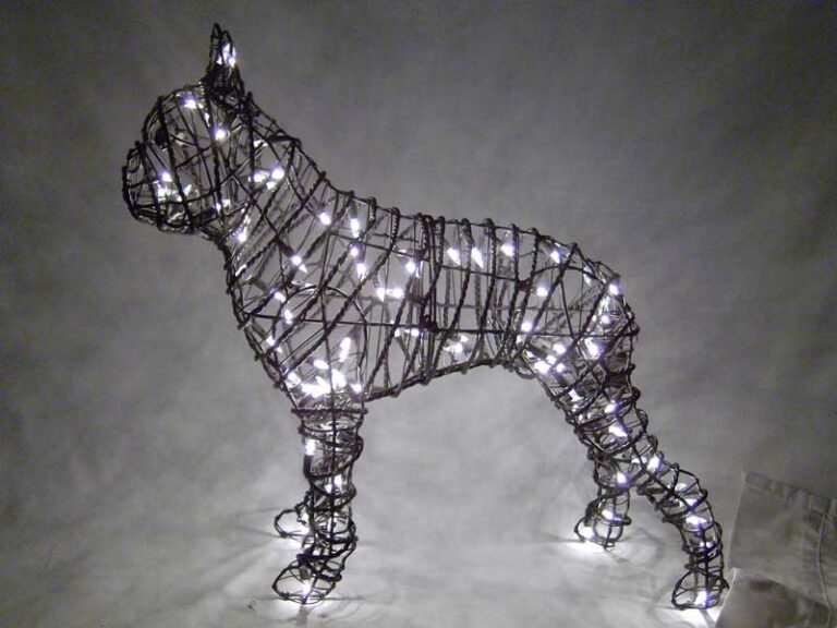Wire frame topiary of a Boston Terrier wrapped in glowing mini lights at night.
