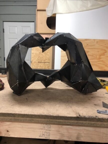 Welded steel panels formed into a heart-shaped hand gesture, on a bench