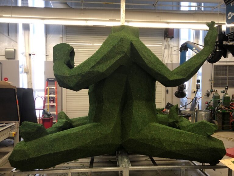 Moss-covered seated figure sculpture, side view