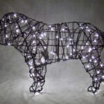 Lit wire bulldog topiary frame strung with small white lights, photographed at night