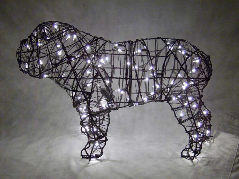 Lit wire bulldog topiary frame strung with small white lights, photographed at night