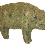 Moss-covered wire-frame pig topiary with a curly tail and bead eye, on a white background