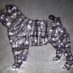 Wire-frame pug topiary lit with small white lights against a dark background