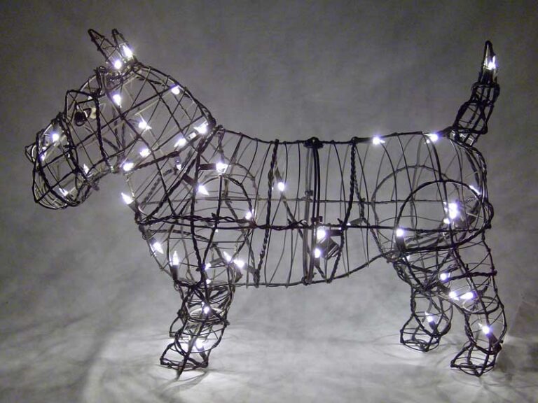 Wire-frame Scottie-dog topiary wound with small white string lights against a dark background