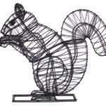 Black wire-frame topiary sculpture of a seated squirrel with a large curled tail, on a rectangular base.