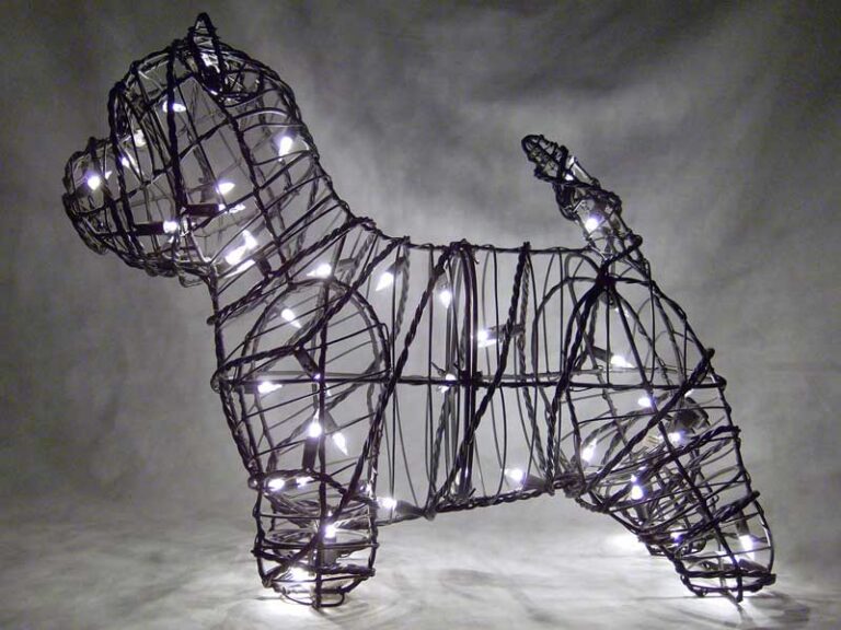 Wire-frame Westie topiary lit with warm white miniature lights, upright ear and short raised tail, dark background