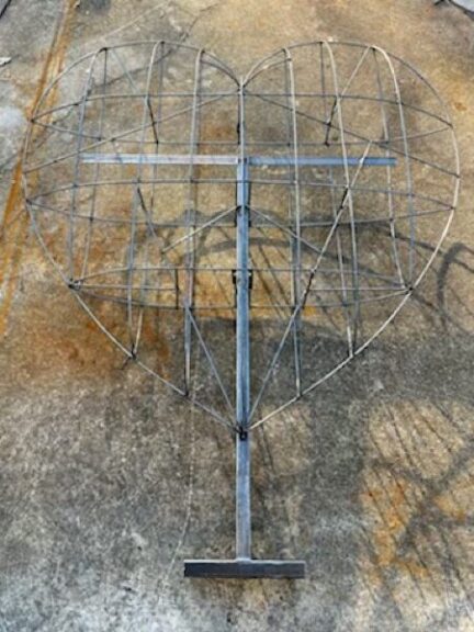 Bare welded wire heart-shaped frame lying on concrete before the moss is applied