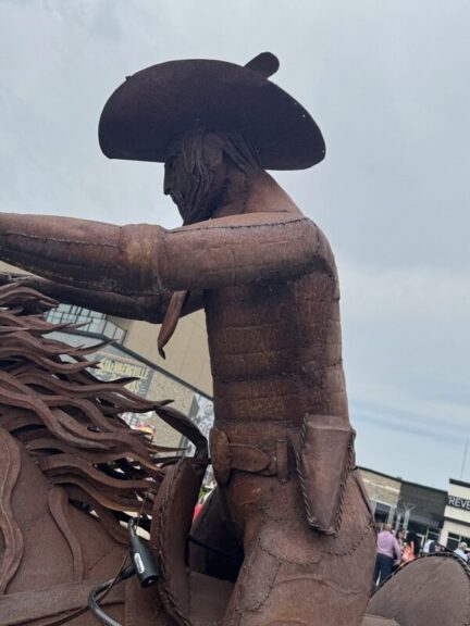 Rear view of the welded-steel cowboy figure showing hat and holster detail