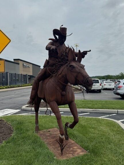 Welded-steel cowboy on a running horse, horse's head and reins in close view