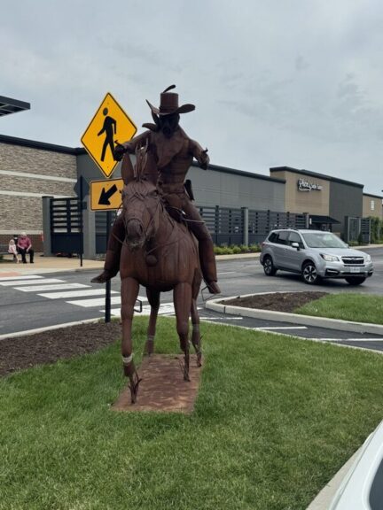 Full view of the welded-steel cowboy-on-horse sculpture installed outdoors