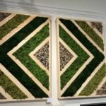 Two moss wall panels in a green diamond and triangle pattern with wood trim and a pebble accent square, mounted on a wall