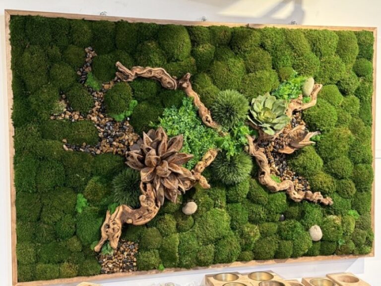An 18x30 framed wall panel of dense green moss with gnarled driftwood branches, river pebbles, small green rosettes and spiky foliage.