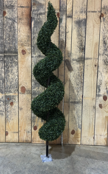 A green spiral topiary on a stone base, against a wood plank wall