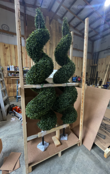Two artificial spiral topiaries crated for shipping, wrapped and secured to a wooden pallet frame