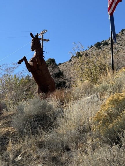 Horse sculpture's head near a utility pole and wires, with a flag edge visible at right