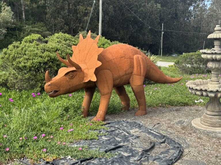 Rust-toned metal triceratops sculpture, close-up view of its horned head and frill