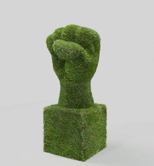 Green artificial-grass raised-fist sculpture on a concrete floor