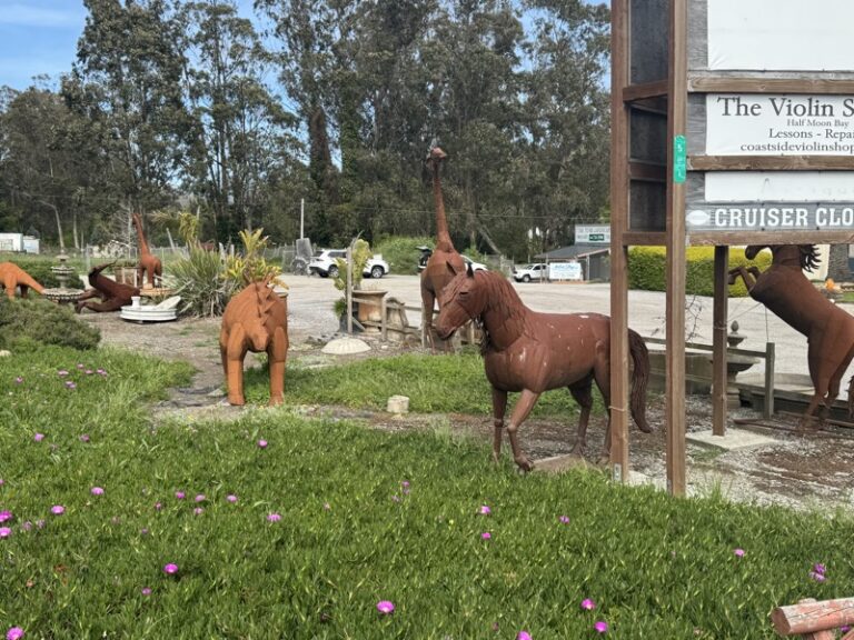 Rearing horse sculpture among several other metal animal sculptures in an outdoor display yard