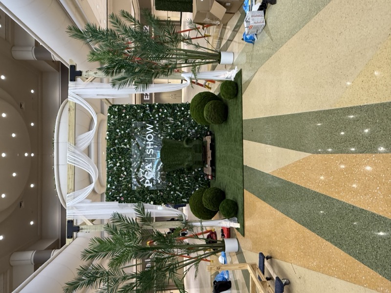 Full topiary exhibition booth at the PGA Show with preserved green wall and turf chair