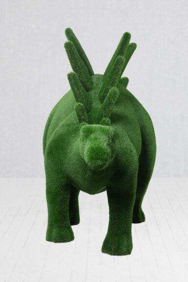 Green artificial-turf stegosaurus sculpture with back plates and a curved tail