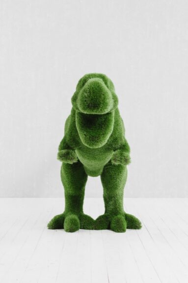 Green T-Rex topiary sculpture covered in artificial turf, standing upright