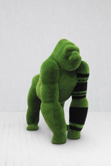 Green grass-textured sculpture in the shape of a standing gorilla