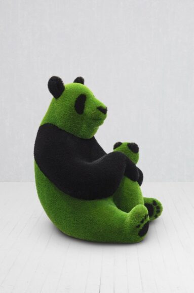 Green turf-covered statue of a panda holding a baby panda, shown on the floor