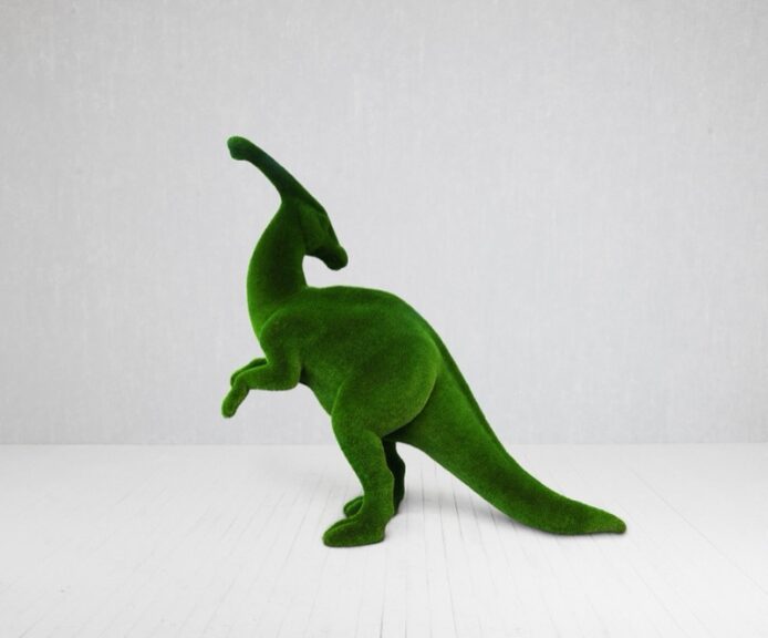 Green velvet-textured dinosaur sculpture in a simplified rounded silhouette, shown on a white background