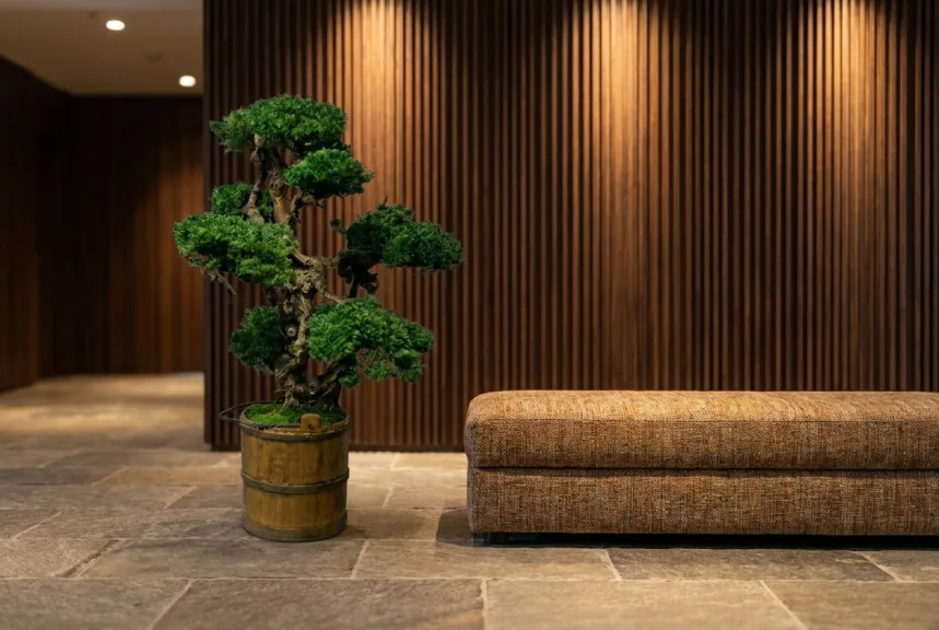 A large preserved bonsai in a banded wooden bucket on a hotel lobby floor