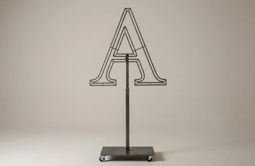 Monogram letter A topiary frame in Cinzel style, bare galvanized steel on an adjustable stand