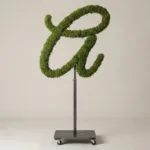 Monogram letter A topiary in Flowing script style, packed with green moss, on an adjustable stand