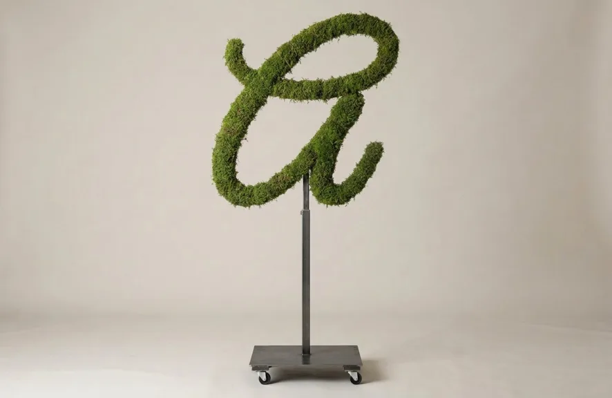 Monogram letter A topiary in Flowing script style, packed with green moss, on an adjustable stand