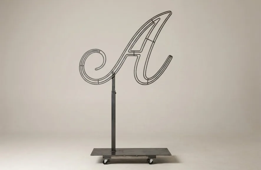 Monogram letter A topiary frame in Script style, bare galvanized steel on an adjustable stand