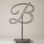 Monogram letter B topiary frame in Flowing script style, bare galvanized steel on an adjustable stand