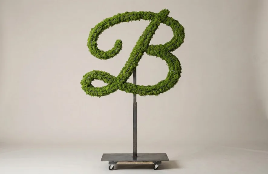 Monogram letter B topiary in Flowing script style, packed with green moss, on an adjustable stand