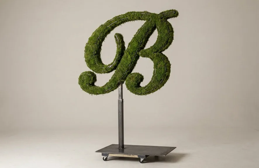 Monogram letter B topiary in Script style, packed with green moss, on an adjustable stand