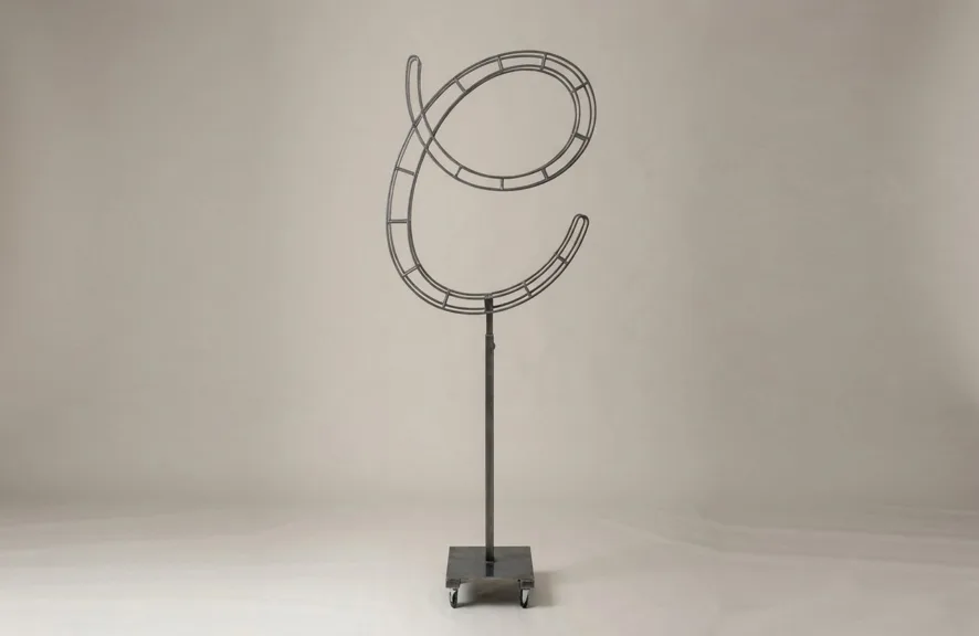 Monogram letter C topiary frame in Flowing script style, bare galvanized steel on an adjustable stand