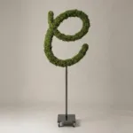 Monogram letter C topiary in Flowing script style, packed with green moss, on an adjustable stand