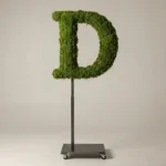 Monogram letter D topiary in Cinzel style, packed with green moss, on an adjustable stand