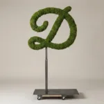 Monogram letter D topiary in Flowing script style, packed with green moss, on an adjustable stand
