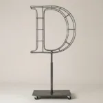 Monogram letter D topiary frame in Roman style, bare galvanized steel on an adjustable stand