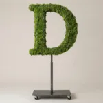 Monogram letter D topiary in Roman style, packed with green moss, on an adjustable stand