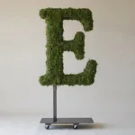 Monogram letter E topiary in Cinzel style, packed with green moss, on an adjustable stand